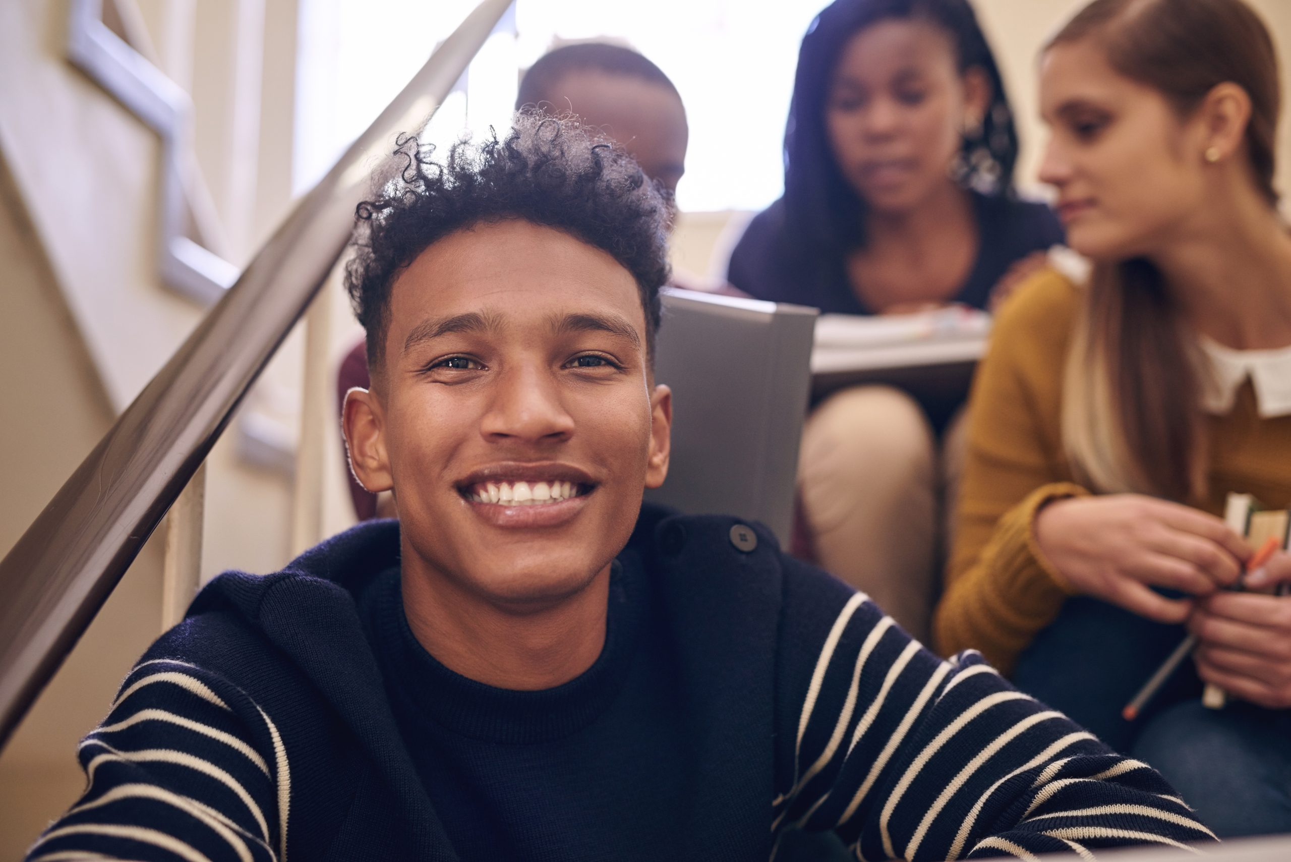 Campus life suits me. Cropped portrait of a handsome young male student sitting on a campus staircase with his friends